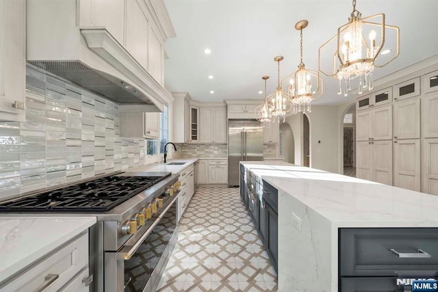 kitchen with a spacious island, white cabinets, decorative light fixtures, and premium appliances