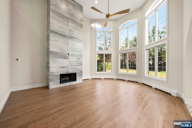 unfurnished living room with a high end fireplace, hardwood / wood-style floors, and plenty of natural light