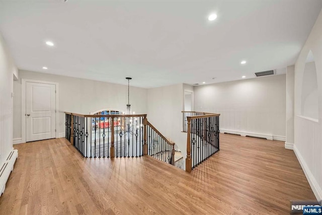 corridor featuring a baseboard heating unit and light wood-type flooring