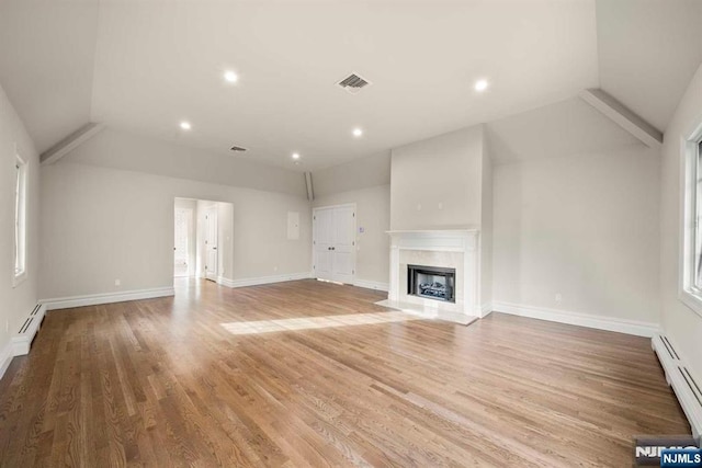 unfurnished living room with hardwood / wood-style flooring, a premium fireplace, and a baseboard heating unit