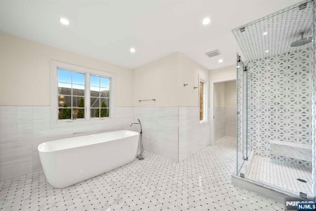 bathroom featuring tile patterned flooring, tile walls, and separate shower and tub