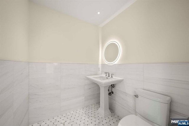 bathroom featuring lofted ceiling, toilet, and tile walls