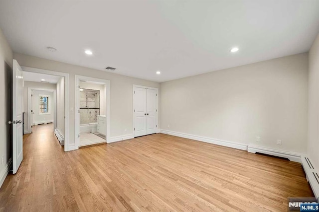 unfurnished bedroom with a baseboard radiator, connected bathroom, and light wood-type flooring