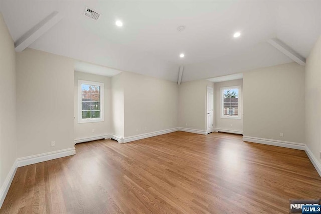 unfurnished living room with hardwood / wood-style flooring and vaulted ceiling with beams