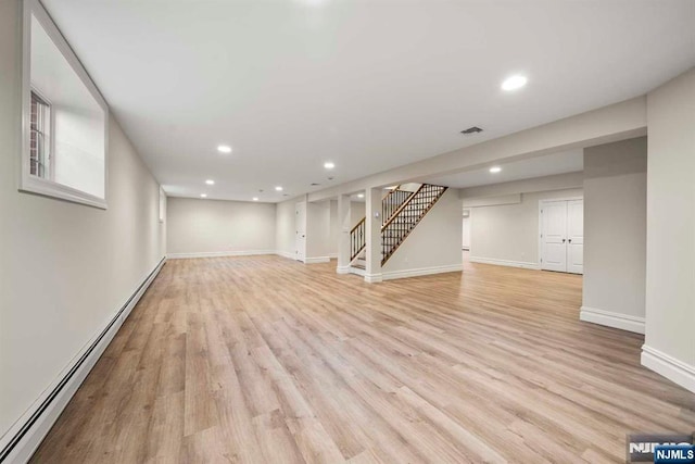 basement with baseboard heating and light hardwood / wood-style floors