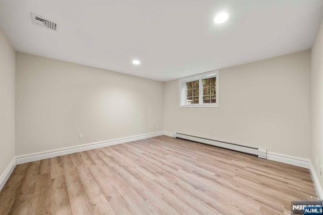 empty room with baseboard heating and light hardwood / wood-style flooring