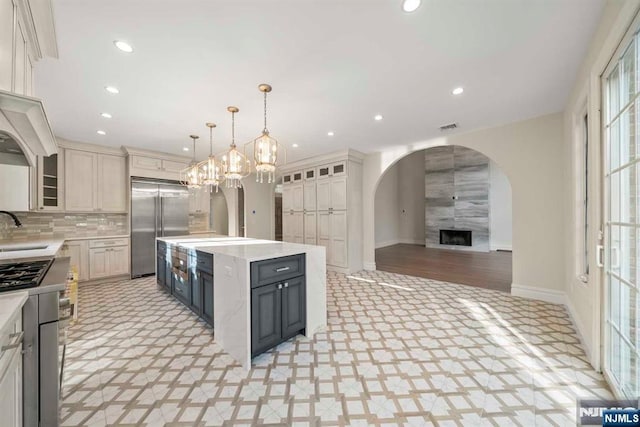 kitchen featuring a kitchen island, tasteful backsplash, sink, hanging light fixtures, and stainless steel appliances