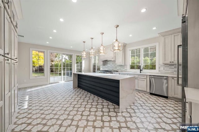 kitchen with pendant lighting, appliances with stainless steel finishes, a center island, and a wealth of natural light