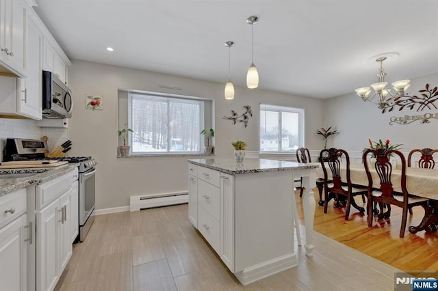 kitchen with appliances with stainless steel finishes, a kitchen island, pendant lighting, white cabinetry, and a baseboard radiator