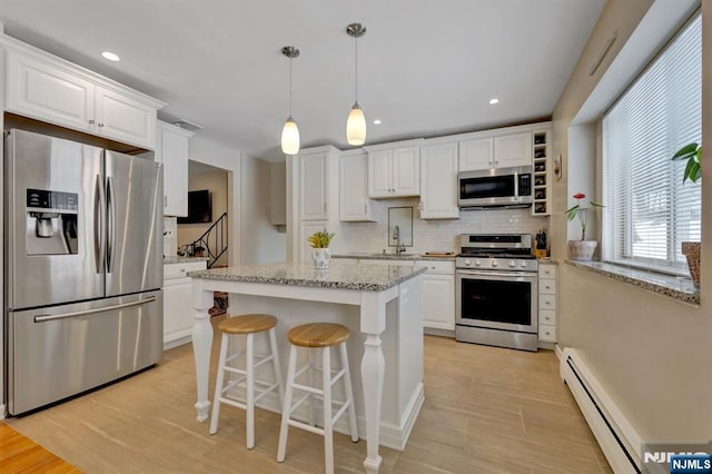 kitchen with white cabinetry, a baseboard heating unit, decorative light fixtures, and stainless steel appliances