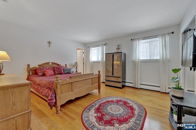 bedroom with multiple windows, a baseboard radiator, and light hardwood / wood-style flooring