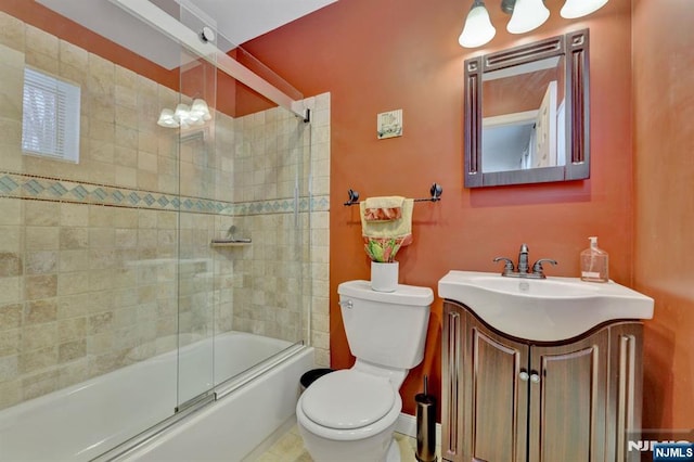 full bathroom featuring vanity, shower / bath combination with glass door, and toilet