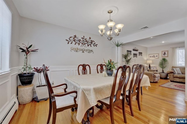 dining space featuring a baseboard heating unit, hardwood / wood-style floors, and a chandelier