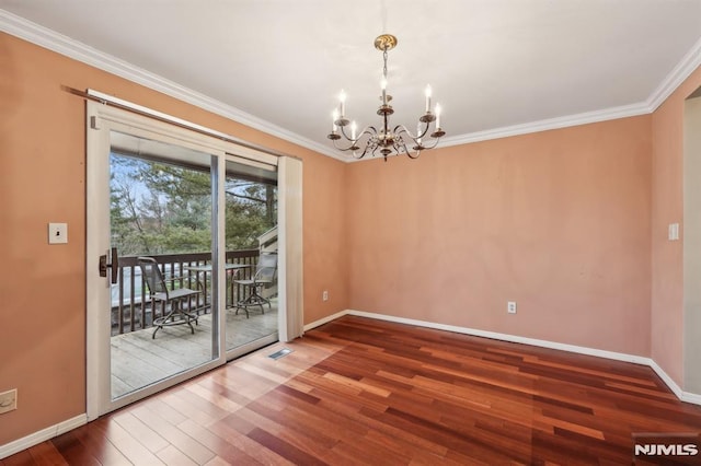 spare room with an inviting chandelier, baseboards, crown molding, and wood finished floors