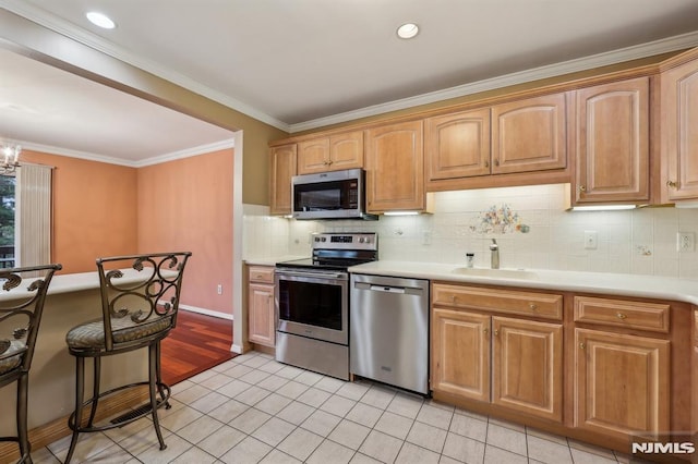 kitchen with light tile patterned floors, a sink, light countertops, appliances with stainless steel finishes, and decorative backsplash