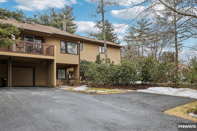 view of front facade with a garage, driveway, and a balcony