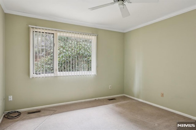 carpeted spare room featuring baseboards, visible vents, ceiling fan, and ornamental molding