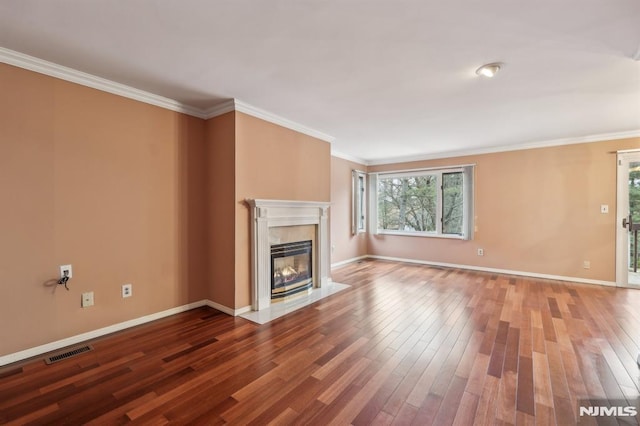 unfurnished living room with crown molding, a premium fireplace, visible vents, and wood finished floors