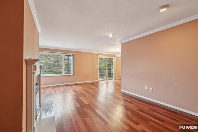 unfurnished living room with baseboards, a fireplace with flush hearth, ornamental molding, and wood finished floors