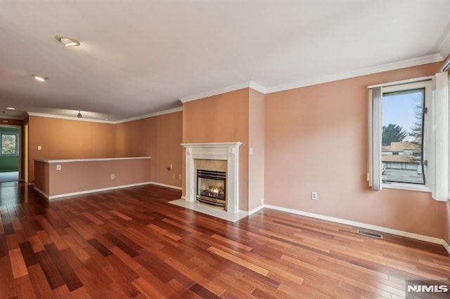 unfurnished living room featuring visible vents, ornamental molding, wood finished floors, a tile fireplace, and baseboards