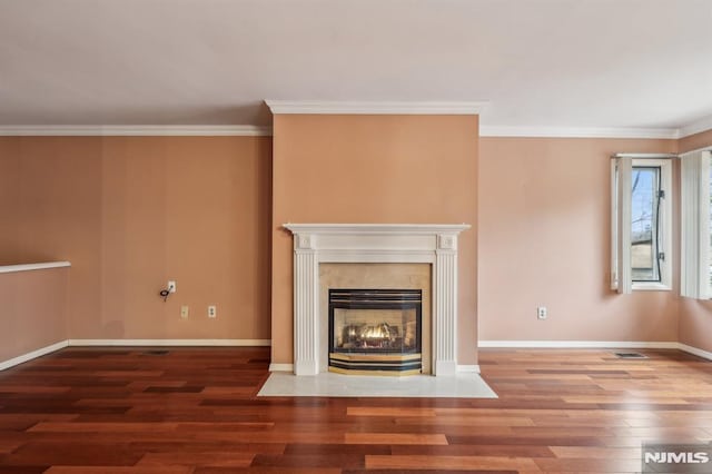 unfurnished living room featuring crown molding, a fireplace, baseboards, and wood finished floors