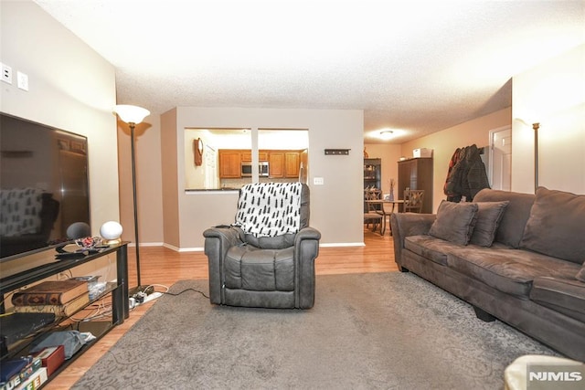 living room with a textured ceiling and light wood-type flooring