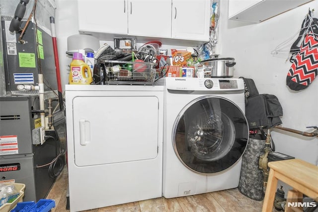 clothes washing area with cabinets, washer and dryer, and light wood-type flooring