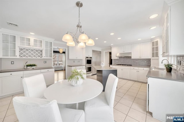 dining area featuring sink, crown molding, light tile patterned floors, and a notable chandelier