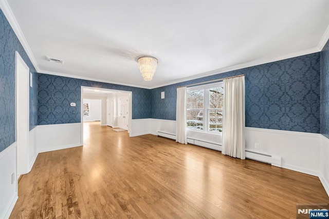 empty room featuring a baseboard radiator, crown molding, hardwood / wood-style floors, and a notable chandelier