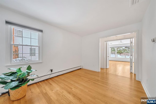 unfurnished room with hardwood / wood-style flooring and baseboard heating