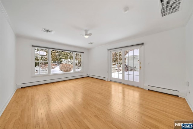 spare room with baseboard heating, a healthy amount of sunlight, and light hardwood / wood-style flooring