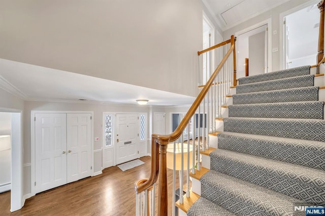 entryway with hardwood / wood-style floors, a towering ceiling, and ornamental molding