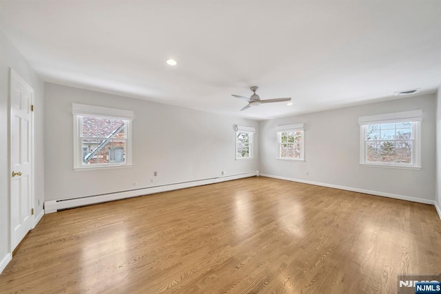 unfurnished room with a baseboard radiator, a healthy amount of sunlight, and light hardwood / wood-style floors