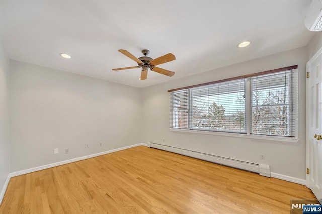 empty room featuring a baseboard heating unit, ceiling fan, light wood-type flooring, and an AC wall unit