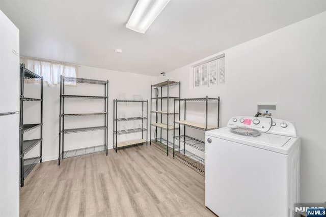 clothes washing area with washer / clothes dryer and light wood-type flooring