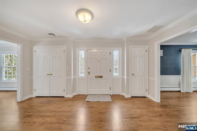 foyer entrance with a baseboard heating unit, hardwood / wood-style flooring, and crown molding