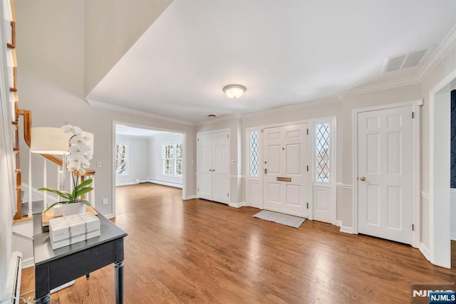 foyer entrance featuring a baseboard heating unit, wood-type flooring, and crown molding