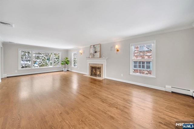 unfurnished living room featuring plenty of natural light, ornamental molding, and baseboard heating