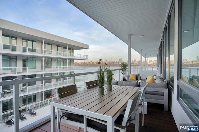 balcony with outdoor dining space and a water view