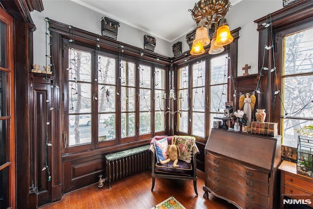 sitting room with hardwood / wood-style floors, radiator heating unit, ornamental molding, and a chandelier