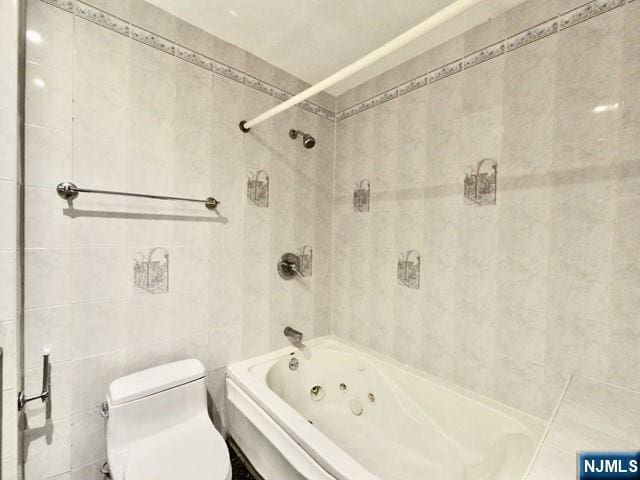 bathroom with tiled shower / bath, tile walls, and toilet