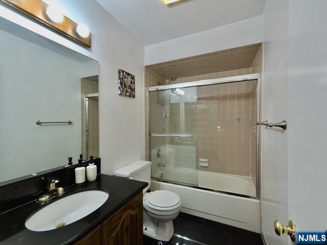 full bathroom featuring shower / bath combination with glass door, tile patterned floors, vanity, and toilet