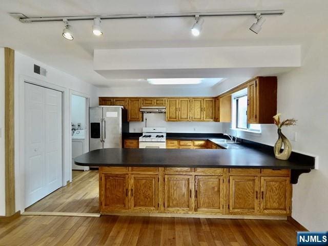 kitchen featuring kitchen peninsula, stainless steel fridge, light hardwood / wood-style floors, and gas range gas stove