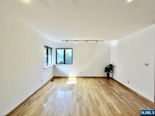 unfurnished room with track lighting and light wood-type flooring