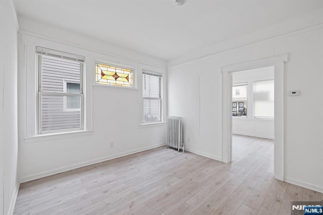 empty room featuring radiator heating unit and light hardwood / wood-style floors