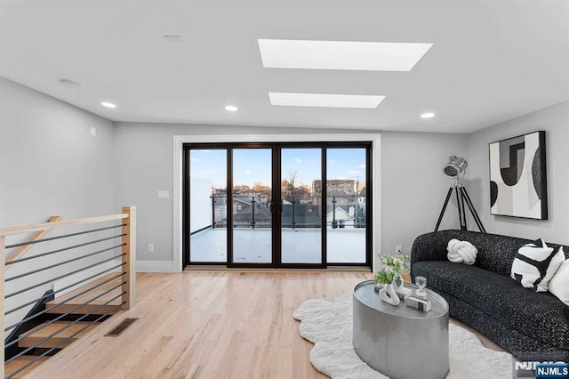 living room featuring a skylight and light hardwood / wood-style floors