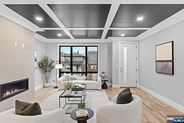 living room featuring beam ceiling, coffered ceiling, a fireplace, and light wood-type flooring