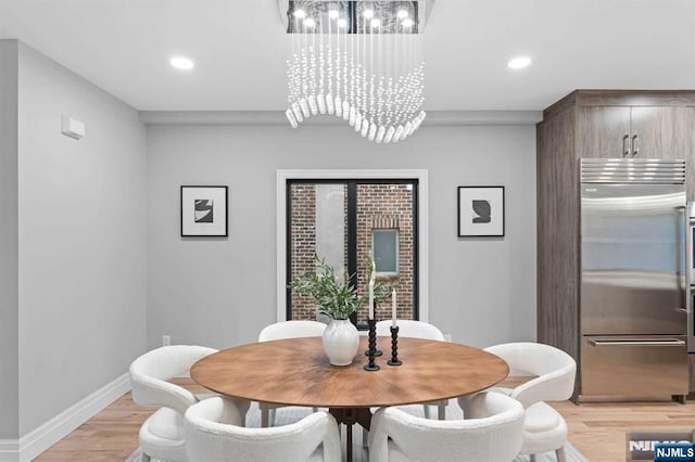 dining area with light hardwood / wood-style flooring and a notable chandelier