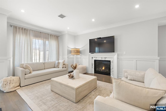 living room with crown molding, a high end fireplace, and light hardwood / wood-style flooring