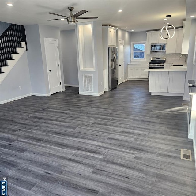 kitchen with backsplash, dark wood-type flooring, stainless steel appliances, and white cabinets